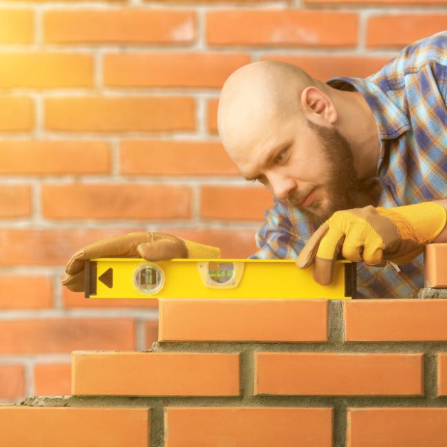 Builder leveling a brick wall